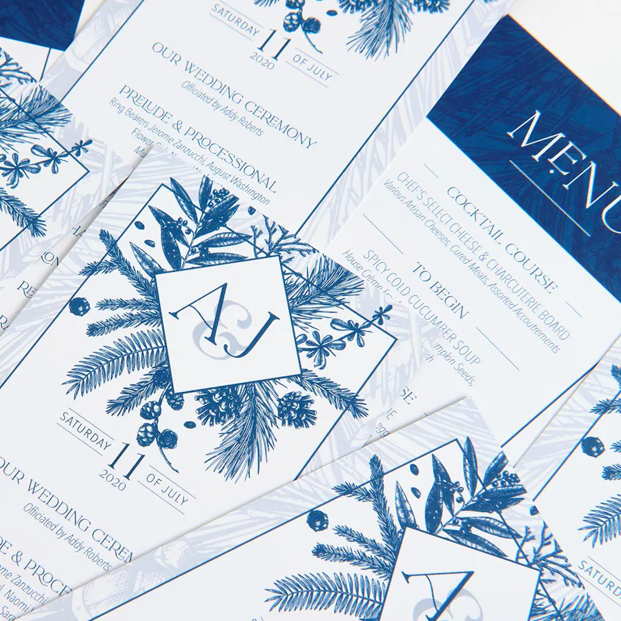 Custom wedding programs with a blue and white design scattered and overlapping each other.