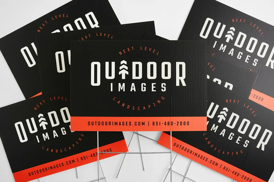 A group of marketing yard signs with a black and red design and Outdoor Images in white letters.