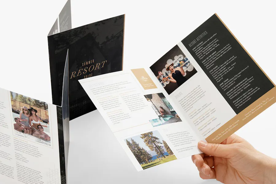 A hand holding a custom brochure open with two more brochures standing open.