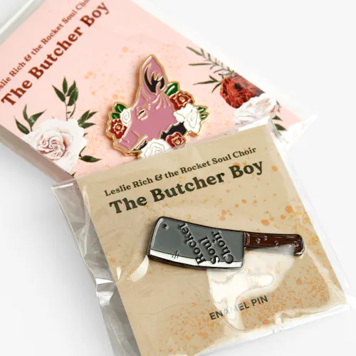 BUSINESS CARDS: TOP: 120# COATED MATTE WHITE COVER, 6 X 2.4" FOLDED TO 3.5 X 2.4". BOTTOM: 120# COATED MATTE WHITE COVER, 2.4 X 2.4" Pig and butcher knife enamel pins on custom backers printed with Leslie Rich & the Rocket Soul Choir.