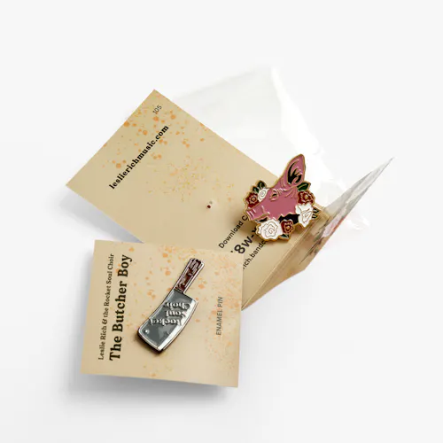 BUSINESS CARDS: TOP: 120# COATED MATTE WHITE COVER, 6 X 2.4" FOLDED TO 3.5 X 2.4". BOTTOM: 120# COATED MATTE WHITE COVER, 2.4 X 2.4" Two enamel pins on custom backers printed with Leslie Rich & the Rocket Soul Choir in tan and black.