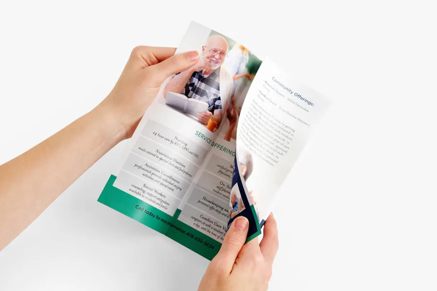 Two hands holding a brochure designed as senior living marketing with details about services and the community.
