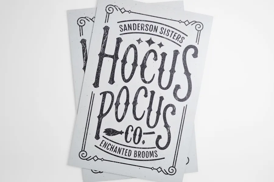 Two overlapping aluminum signs with Sanderson Hocus Pocus Co. Enchanted Brooms printed on them.
