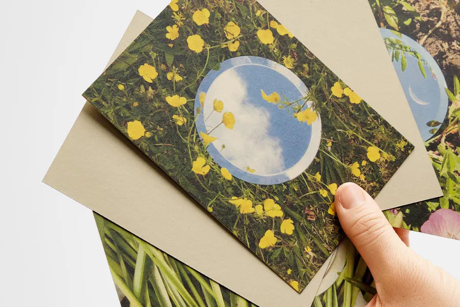 A hand holding fanned-out cards and envelopes printed on hemp paper.