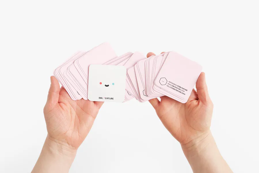 Two hands holding fanned-out square business cards that are used as package inserts.