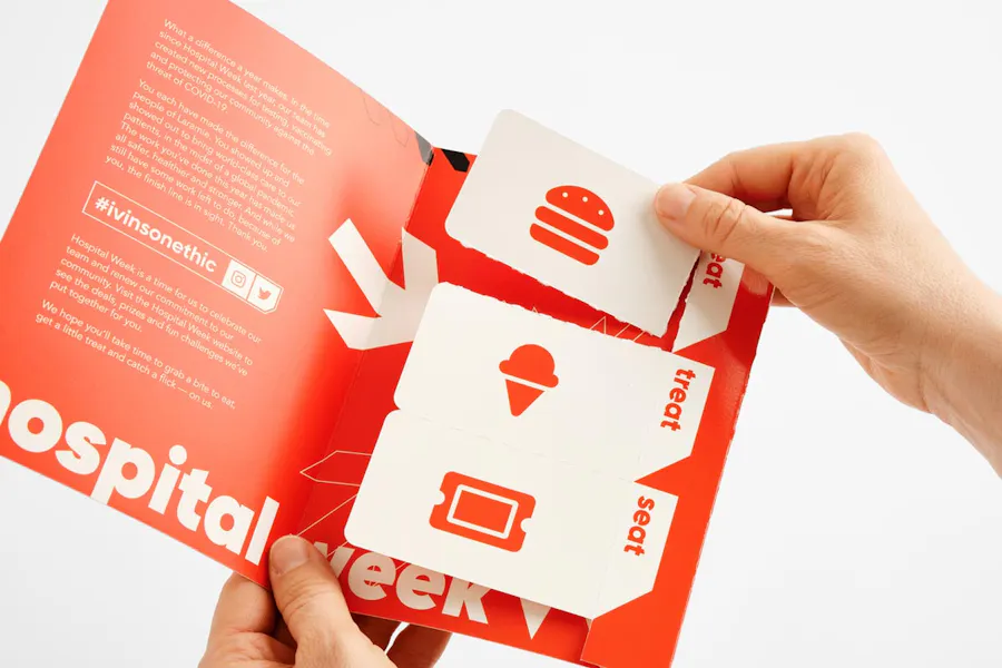 Two hands holding a coupon mailer with three perforated coupons and an orange design.