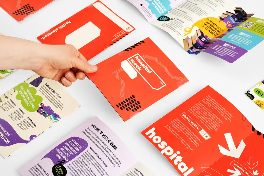 A hand holding an orange coupon mailer among other direct mailers with a purple, blue and green design.