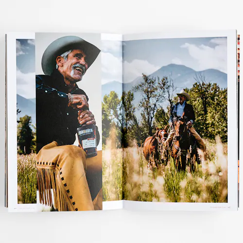 A brand book laying open to images of a man holding a bottle of whiskey and riding a horse.
