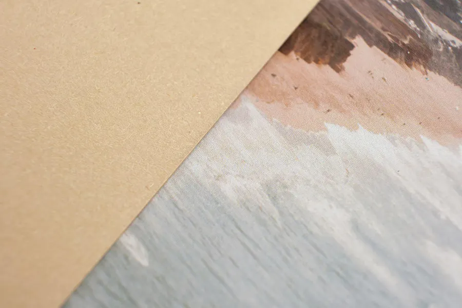 A piece of hemp paper stock overlapping a custom card printed with a muted ocean and beach scene.