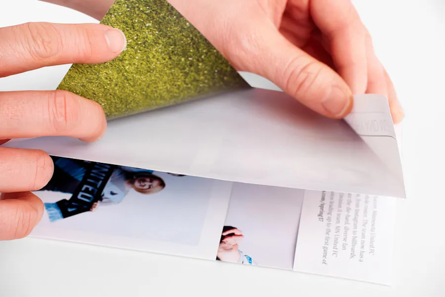 Two hands folding a broadside reveal brochure.