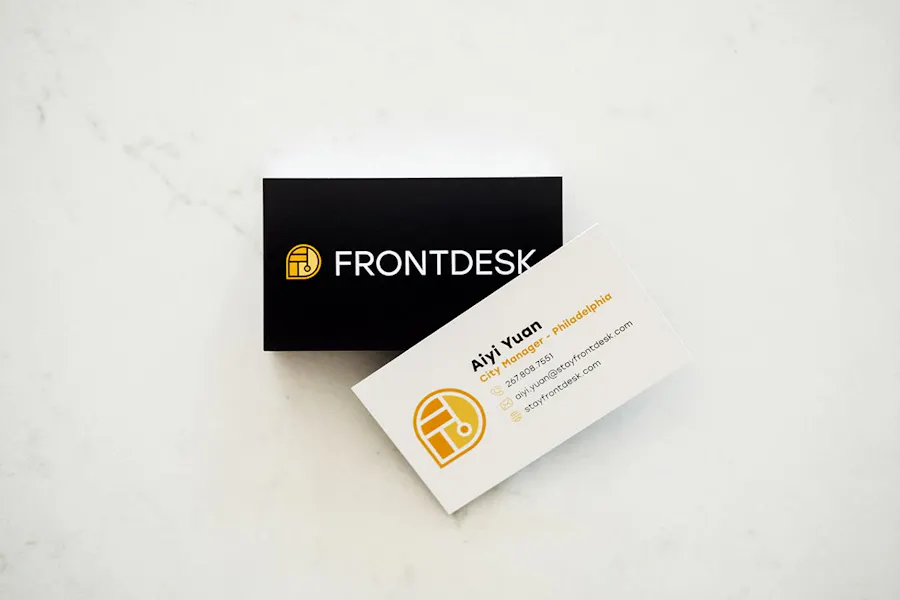 Two custom business cards with a black design and Front Desk on the front and contact information on the back.