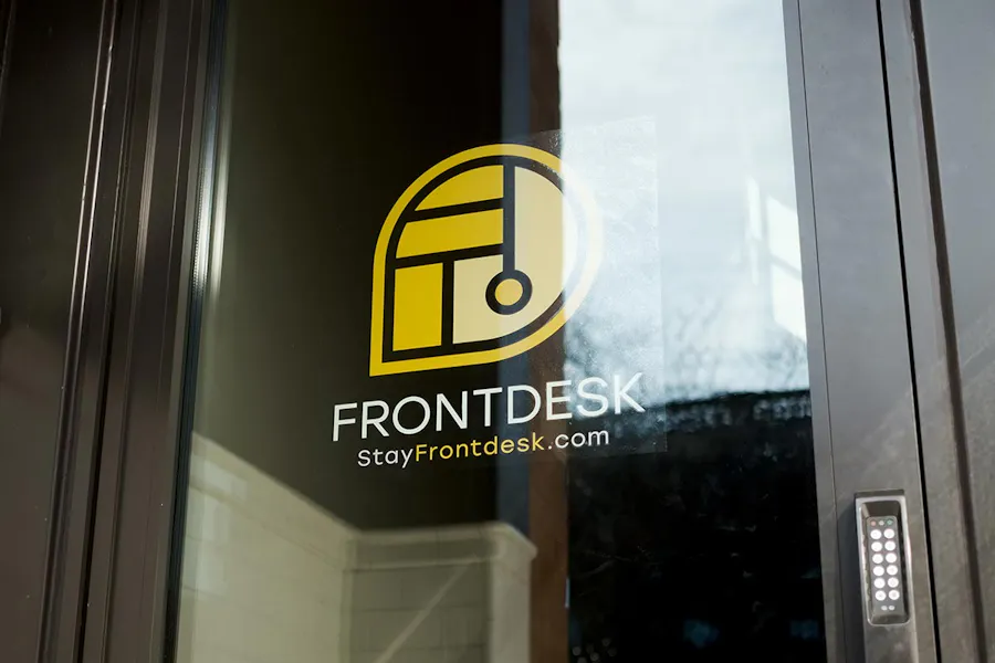 A decal in a window with Front Desk in white letters and a yellow logo above it.