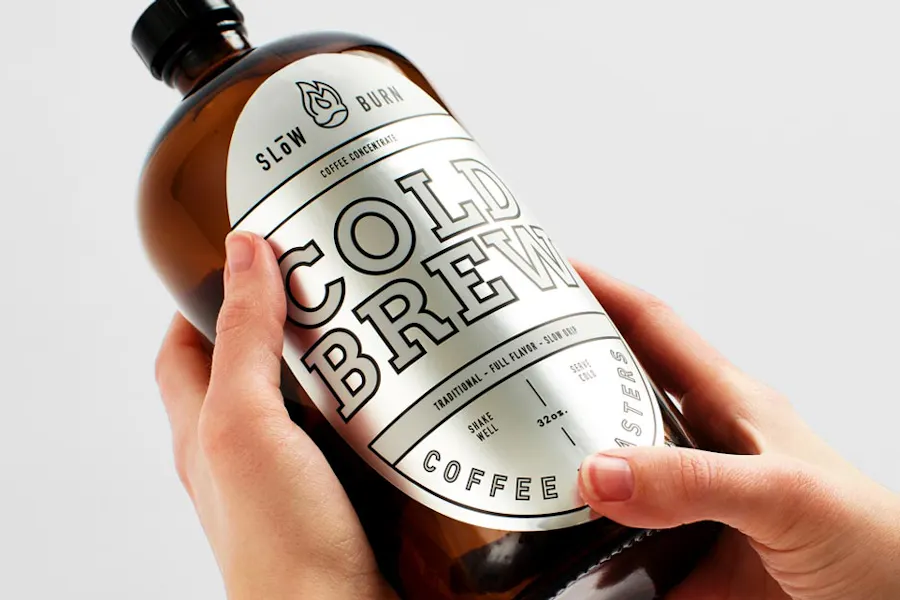 Two hands holding a bottle of cold brew with a silver product label.