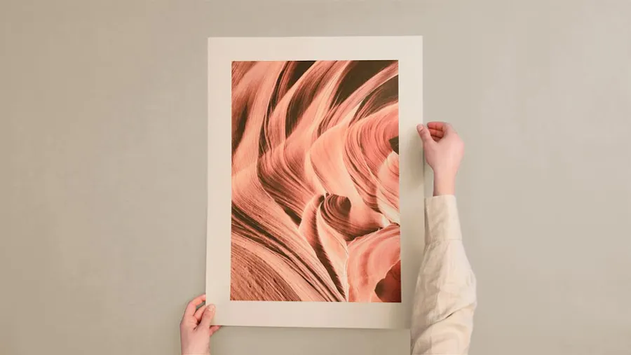 Two hands holding a poster printed on recycled paper stock with an abstract design in coral color.