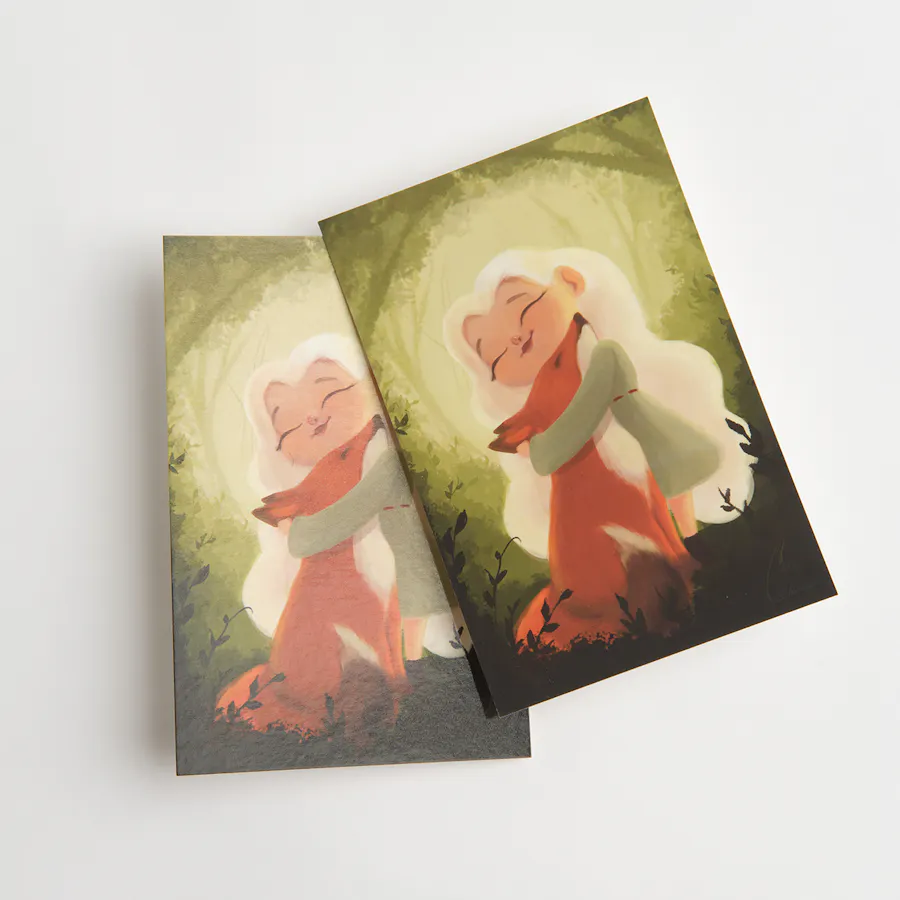 Two postcards printed with a graphic of a little girl hugging a fox and finished with Soft Touch laminate.