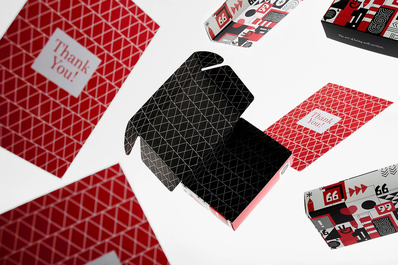 A custom tuck box open to a black and white interior with thank you cards and other product packaging around it.