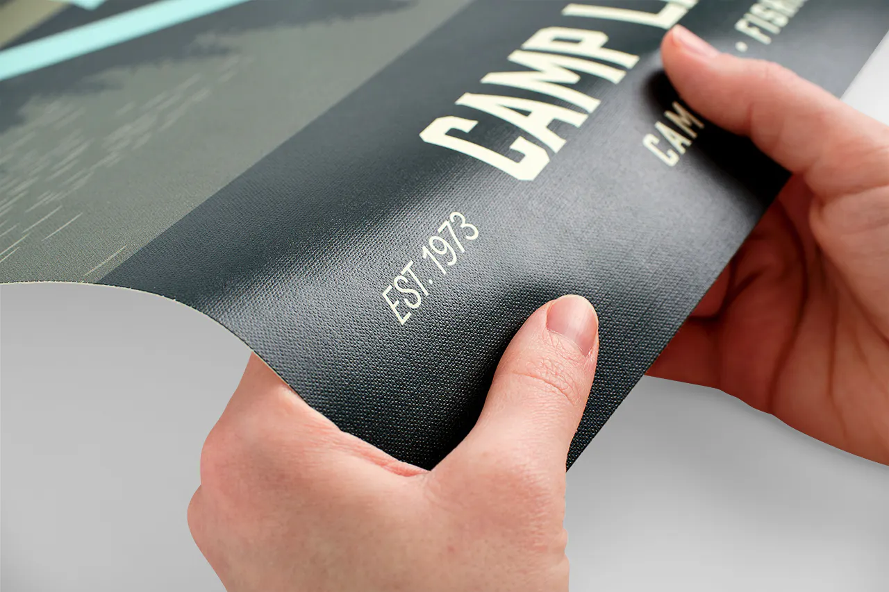 Two hands bending a textured wall decal printed with Camp Lakeland.