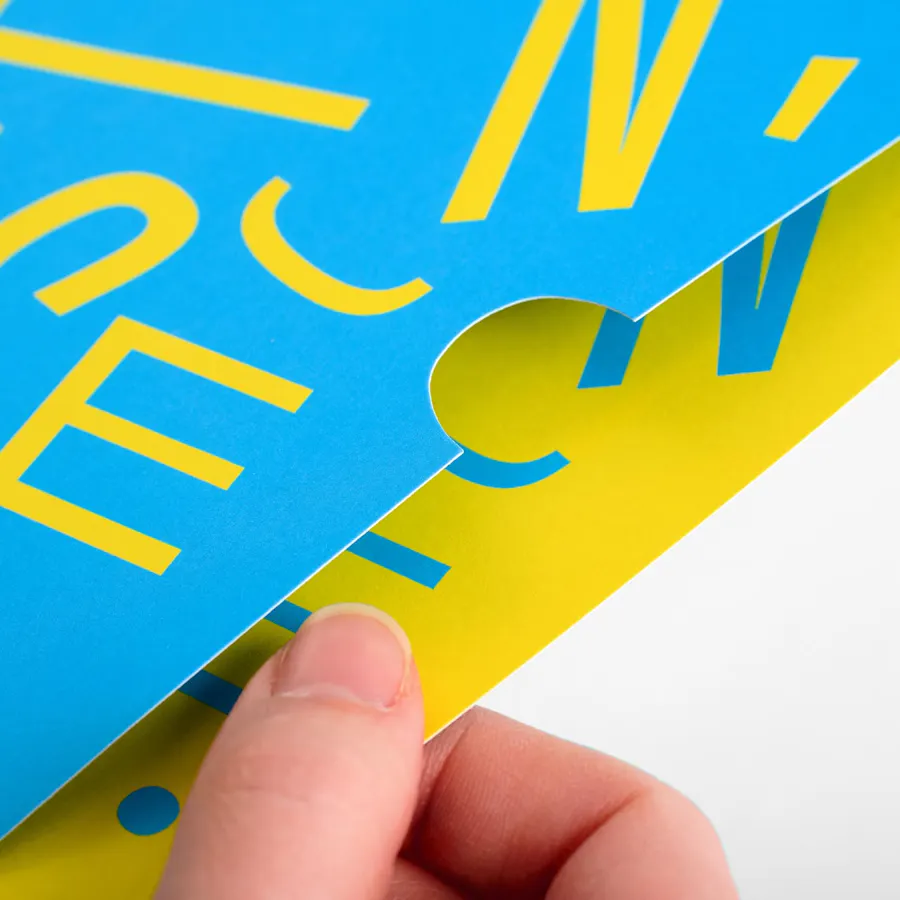 A hand pulling a yellow insert card out of a blue mailing sleeve.