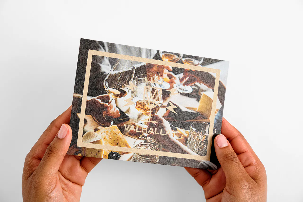 Two hands holding an insert card printed on Kraft paper with Valhalla Wine Shop on the front.