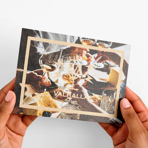 Two hands holding an insert card printed on Kraft paper with Valhalla Wine Shop on the front.