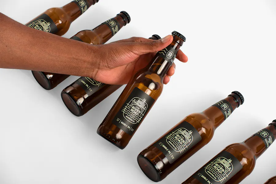 Six beer bottles lined up in a row with custom labels printed with River Road Brewing Co.