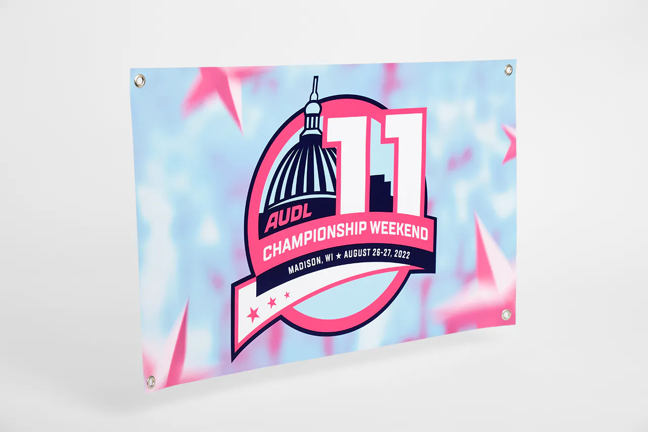 A custom hanging banner with grommets in the corners and printed with AUDL Championship Weekend 11 in blue, pink and white.