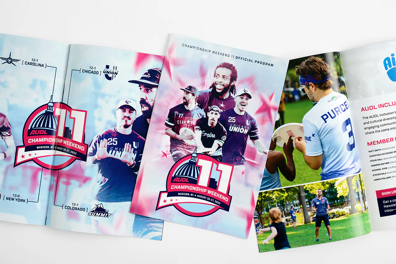 Three event programs for AULD Championship Weekend 11 printed with a saddle stitch binding and laying open to images of ultimate disc players.
