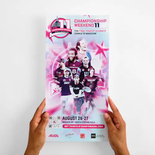 Two hands holding a custom poster printed with a blue, white and pink design, images of ultimate disc players and details about championship weekend.