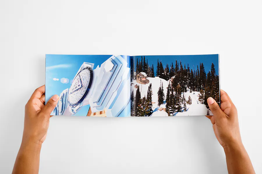 Two hands holding open a photography portfolio with images of a snow-covered mountain.
