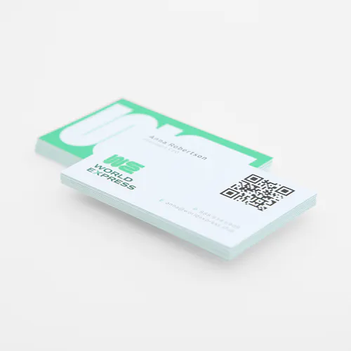 Two stacks of business cards printed with a green and white design, contact information and a QR code for marketing.