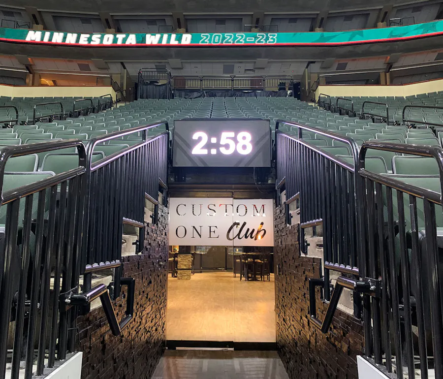 The entrance to the Custom One Club at the Xcel Energy Center with a large digital clock above the glass doors.