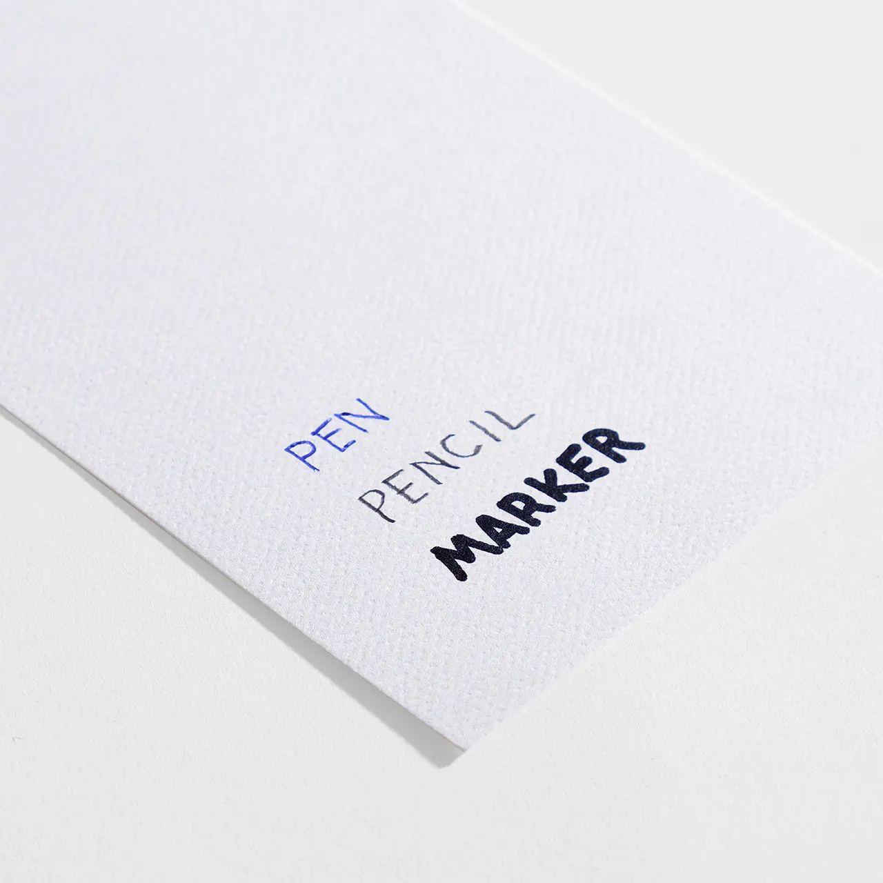 Felt weave paper stock with pen, pencil and marker written on it.