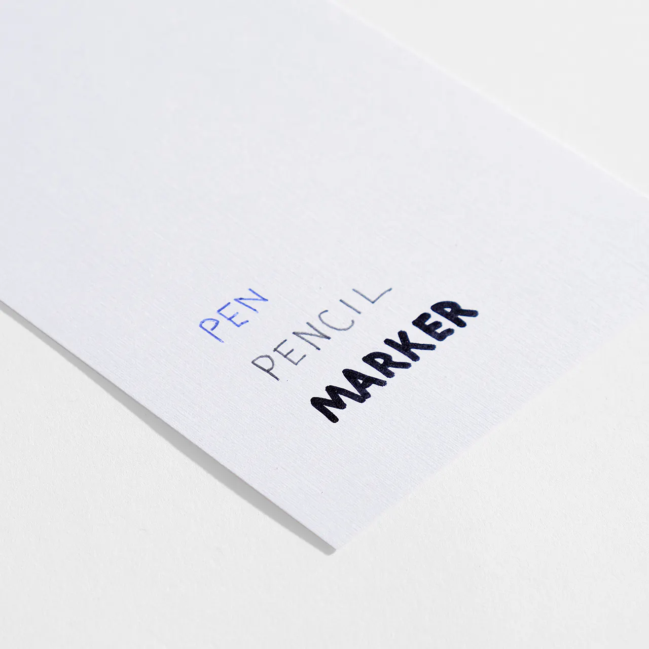 Linen paper stock with pen, pencil and marker written on it.