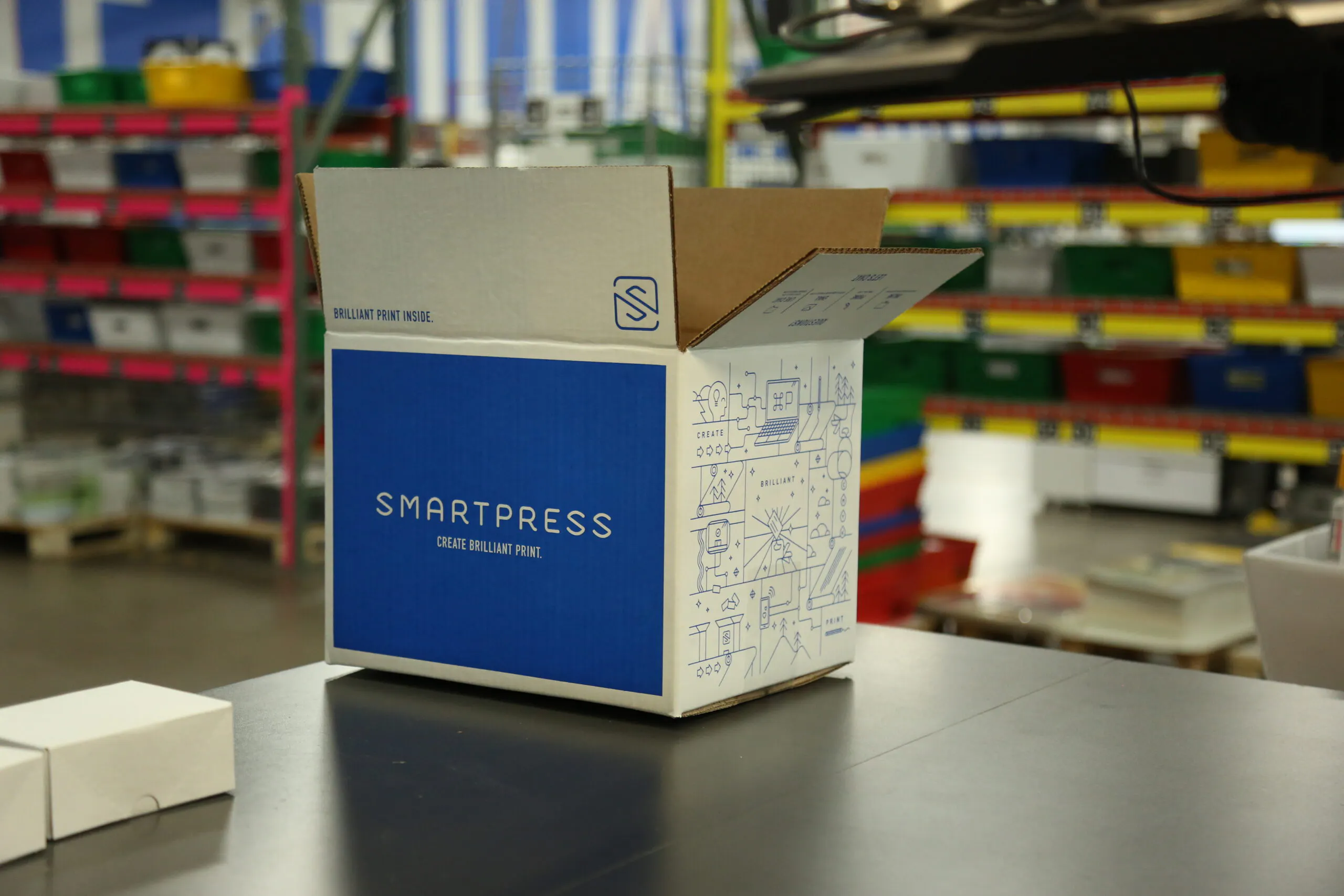A sustainable packaging box printed with Smartpress branding sitting on a table in a production facility.