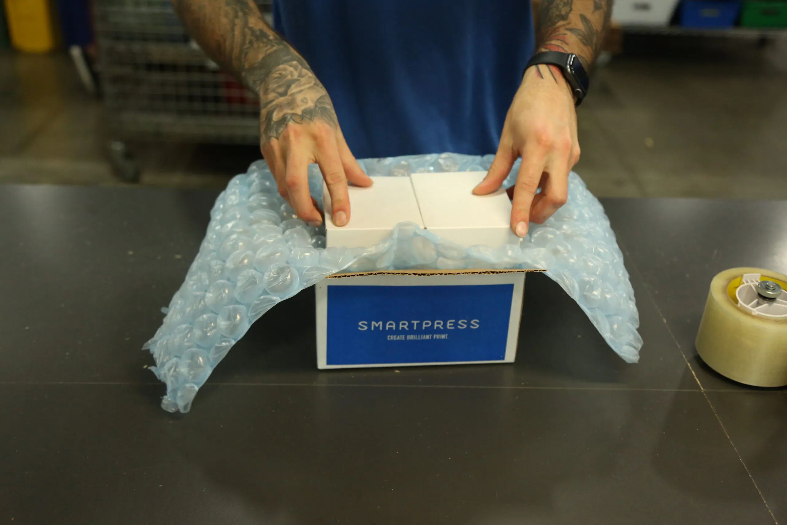 Two hands putting a product into a sustainable packaging box printed with Smartpress on the side.