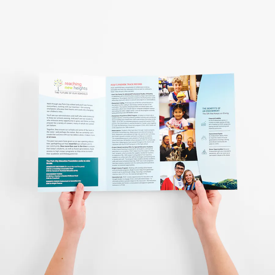 Two hands holding open a tri fold pocket mailer printed with school information and images.