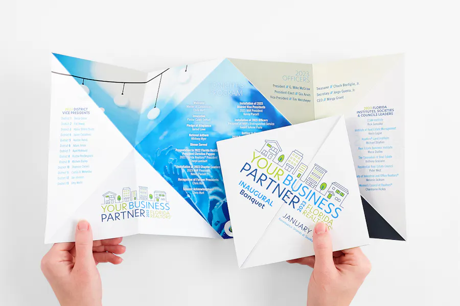 Two hands holding a custom brochure folded and unfolded and printed with banquet details.
