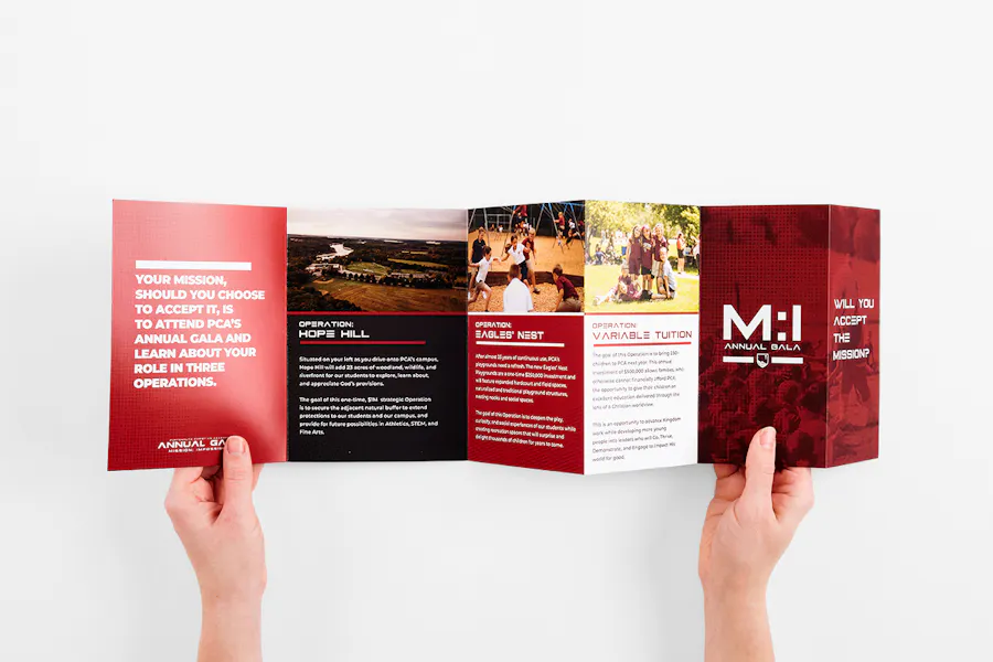 Two hands holding open a custom brochure printed with an accordion fold and a red, black and white design.