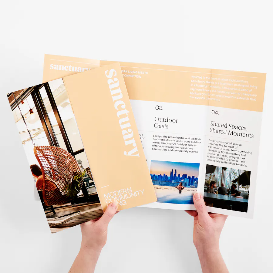 Two hands holding fanned out brochures printed with Pantone Color of the Year 2024 Peach Fuzz.