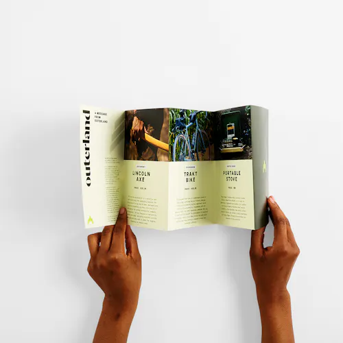 Two hands holding open a custom brochure printed with five panels and info about outdoor gear.