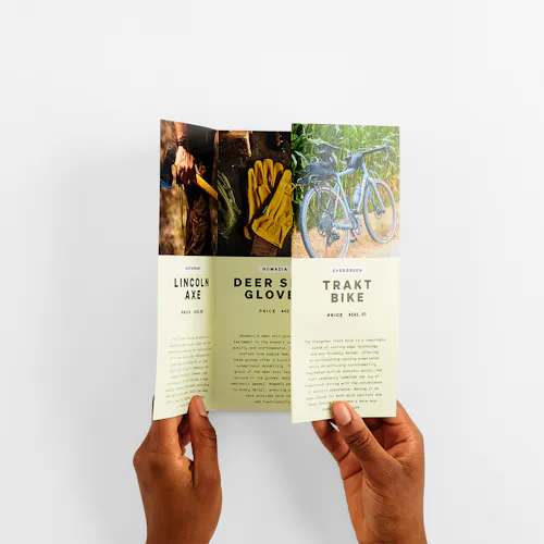 Two hands holding a product brochure printed with a double parallel fold and outdoor gear details.