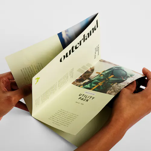 Two hands holding a custom brochure printed with a double fold and outdoor gear details.