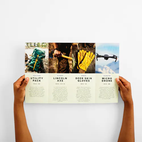 Two hands holding open a gate fold brochure printed with images and details of outdoor gear.