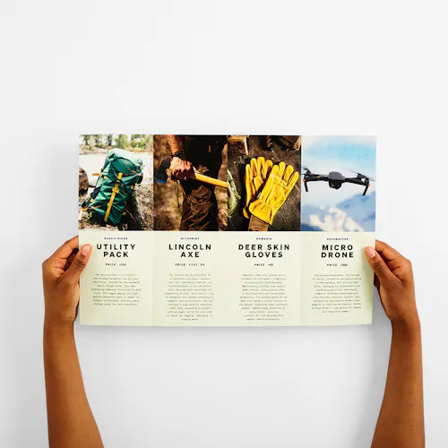 Gate Fold Two hands holding open a gate fold brochure printed with images and details of outdoor gear.