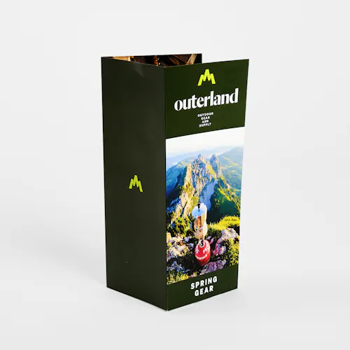 A tri-fold brochure standing open and printed with a dark green design and Outerland Spring Gear.