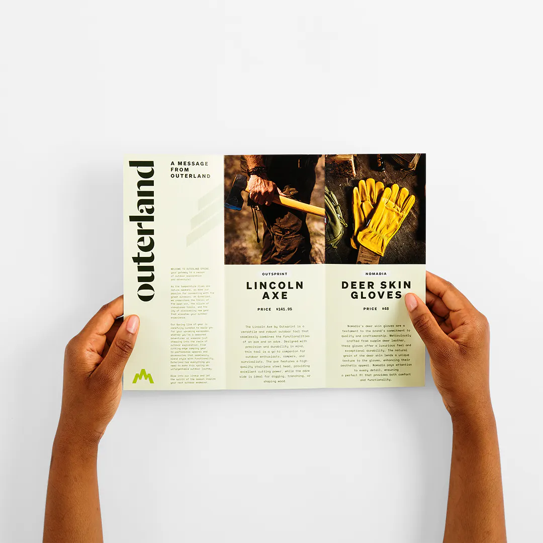 Two hands holding a tri-fold brochure open to images and details for outdoor gear.