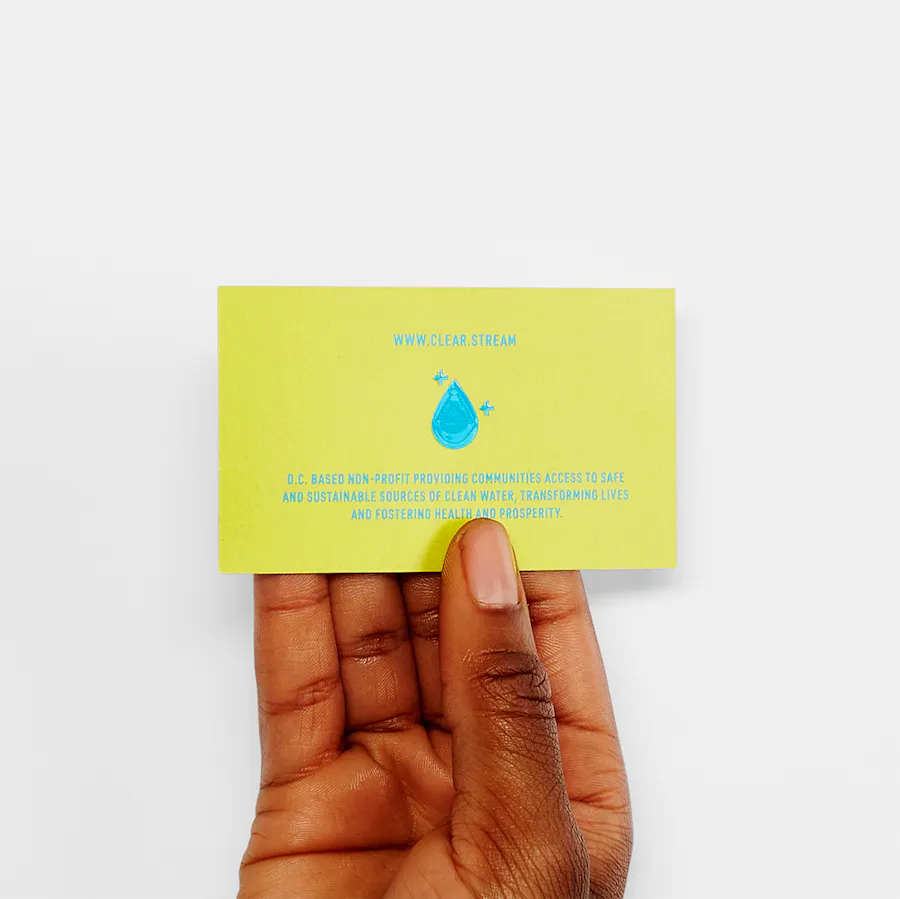 A hand holding a custom business card printed with a raised UV coating, yellow background and blue text.