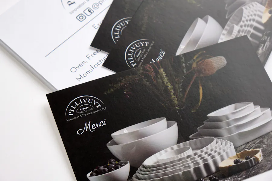 A stack of marketing postcards printed with white tableware and Pillivuyt Merci in white.