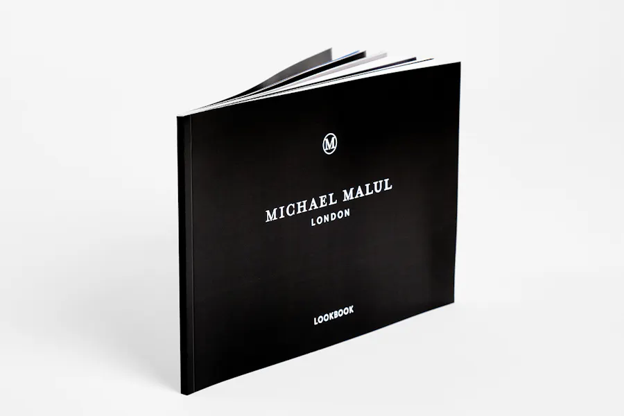 A custom lookbook standing on its side and printed with Michael Malul London and a black background.