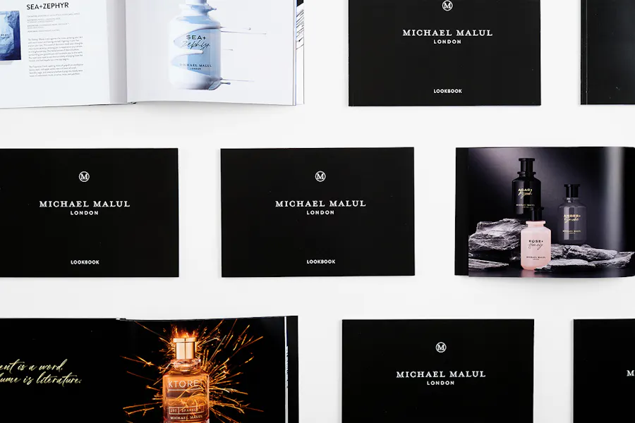 Custom lookbooks lined up in three rows and printed with a black and white cover and images of fragrances.